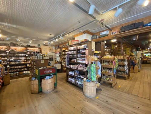 Interior of a rustic store with wooden shelves filled with various products, including snacks and beverages.