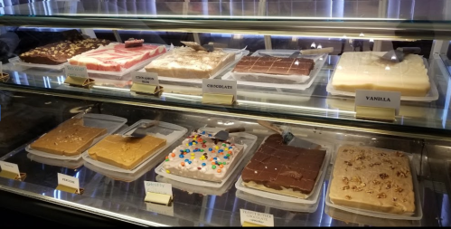 A display case filled with various fudge flavors, including chocolate, vanilla, and colorful toppings.