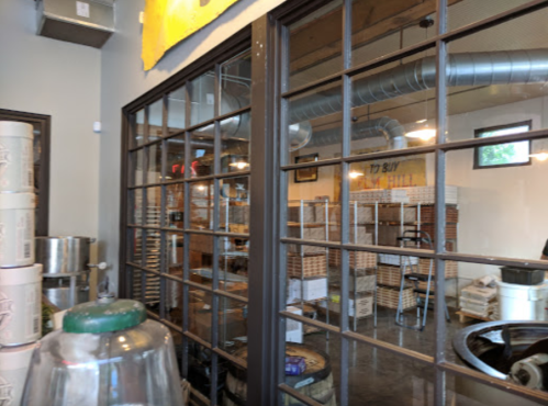 Interior view of a room with large windows, showcasing shelves and storage in a cozy, industrial-style space.