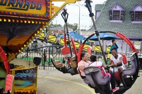 A colorful amusement ride called "Tornado" with people enjoying the experience at a fairground.