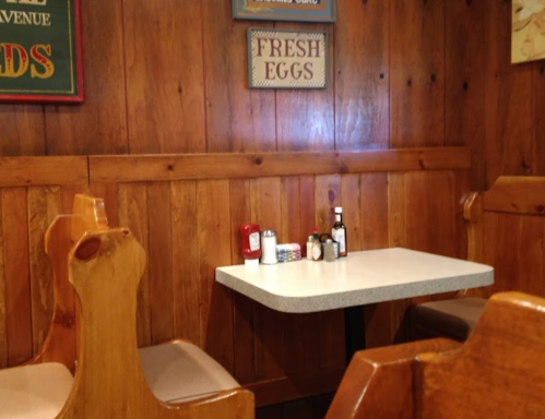 A cozy diner corner with wooden walls, a small table, and condiments on it.
