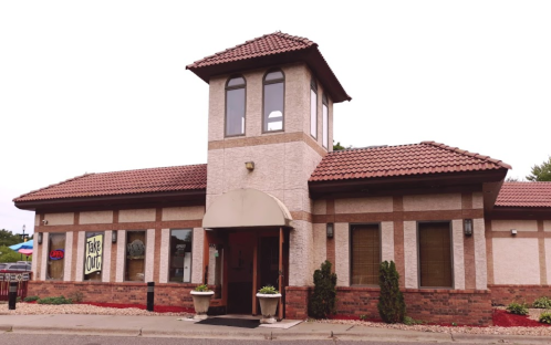 A restaurant building with a tower, featuring a takeout sign and landscaped entrance.