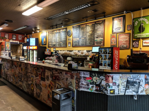 A vibrant restaurant counter with a menu board, colorful decor, and a staff member preparing food.