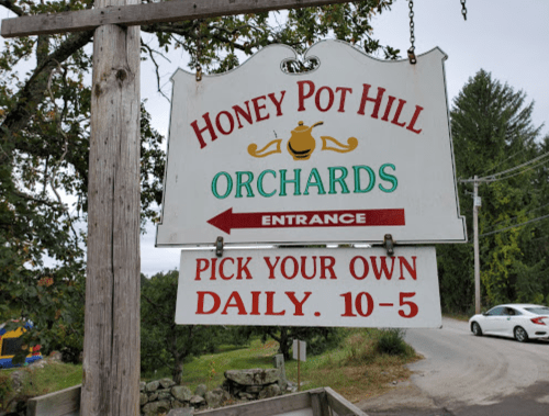 Sign for Honey Pot Hill Orchards, indicating entrance and hours for picking your own fruit daily from 10 AM to 5 PM.