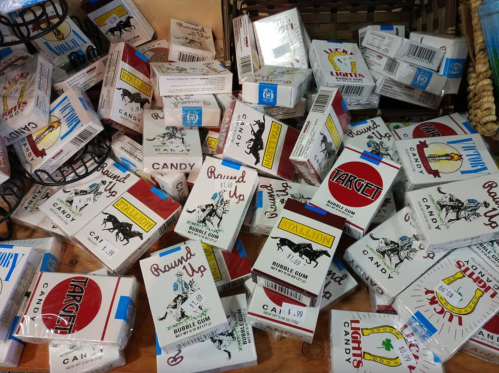 A colorful assortment of candy boxes scattered on a wooden surface, featuring various brands and designs.