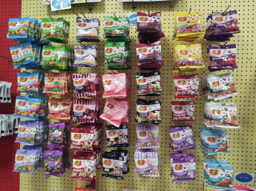 A colorful display of various jelly bean packages arranged on a pegboard wall.