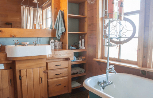 Cozy bathroom with wooden accents, a vintage sink, a freestanding tub, and natural light from a window.