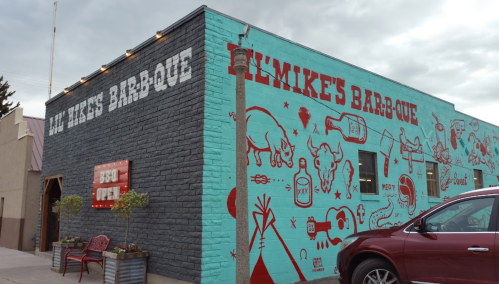 Colorful mural on a barbecue restaurant featuring food and drink illustrations, with a "BBQ Open" sign.
