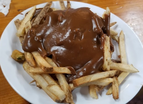 A plate of French fries topped with a thick brown gravy.