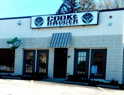 Exterior of Cook & Dagger restaurant, featuring a sign and an open flag, with a wheelchair-accessible entrance.