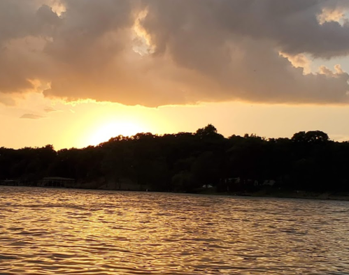 A serene sunset over a calm lake, with silhouettes of trees against a colorful sky.