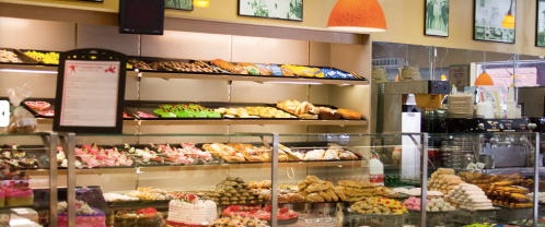 A bakery display filled with various pastries, cookies, and desserts under warm lighting.