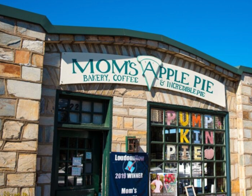 Exterior of Mom's Apple Pie bakery, featuring a stone facade and a sign with "Pumpkin Pie" displayed in the window.
