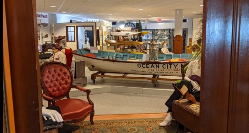 View of a museum exhibit featuring a vintage boat labeled "OCEAN CITY" and displays of maritime artifacts.