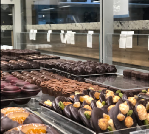 A display case filled with an assortment of elegant chocolates and confections in various shapes and sizes.