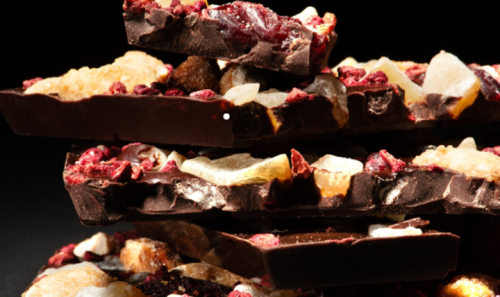 A stack of dark chocolate bark topped with dried fruits and nuts, showcasing a rich texture and vibrant colors.