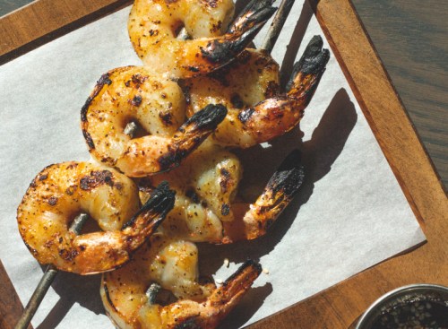 Grilled shrimp skewers on a wooden platter, garnished and ready to serve.