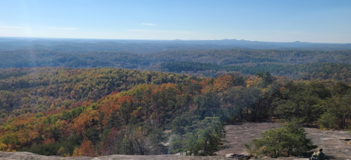 A panoramic view of a colorful autumn landscape with rolling hills and trees in vibrant fall foliage.