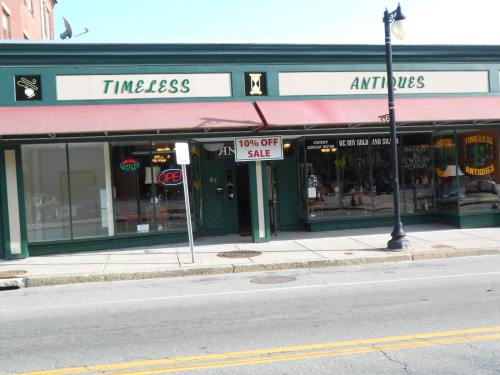 Storefront of "Timeless Antiques" with a sale sign, open sign, and large windows displaying antiques.