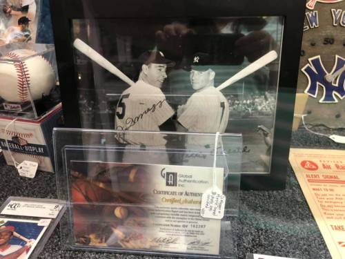 Framed black-and-white photo of two baseball players with bats, surrounded by memorabilia and a certificate of authenticity.