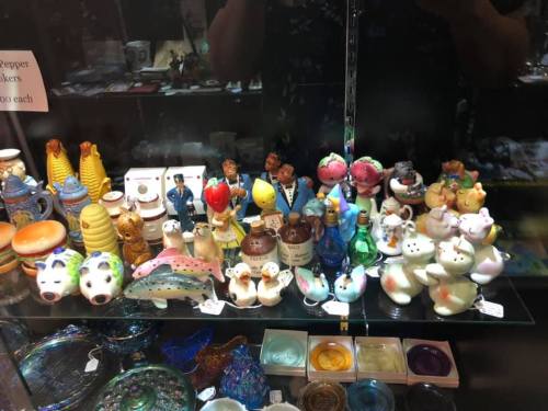 A display of colorful ceramic figurines and collectibles on shelves, including animals and various characters.