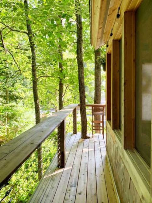 A wooden deck surrounded by lush green trees, leading to a cozy cabin in a serene forest setting.