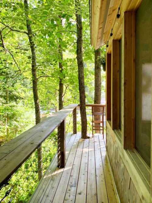 A wooden deck surrounded by lush green trees, leading to a cozy cabin in a serene forest setting.