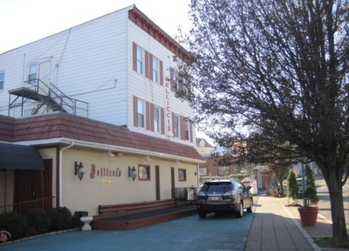 A building with a sign reading "Pellicci's," featuring a tree and parked car in front on a sunny day.