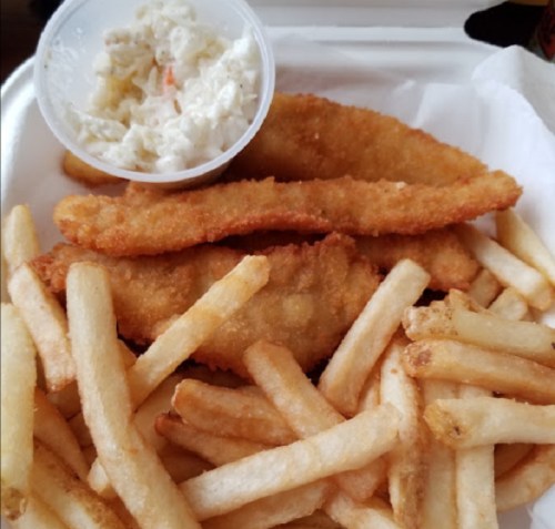 A plate of golden fried fish fillets served with a side of coleslaw and a generous portion of French fries.