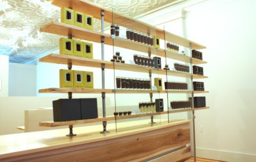 A wooden display shelf with various black and yellow product boxes arranged neatly in a modern interior space.