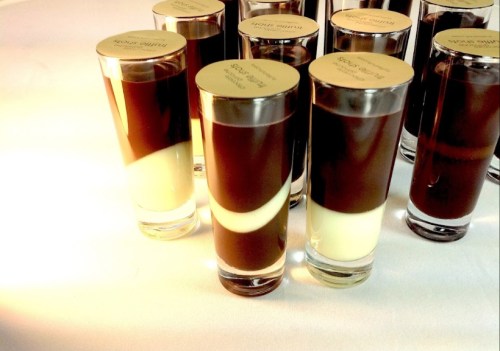 A close-up of dessert shots in clear glasses, featuring layers of chocolate and cream.