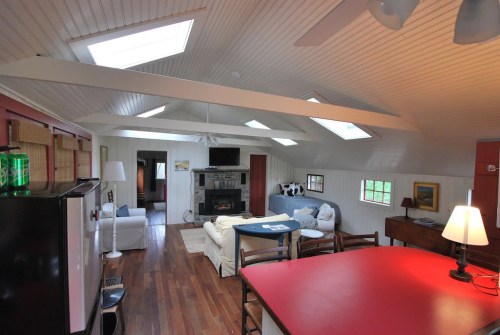 Bright, open living space with skylights, wooden floors, a cozy sofa, and a dining area.