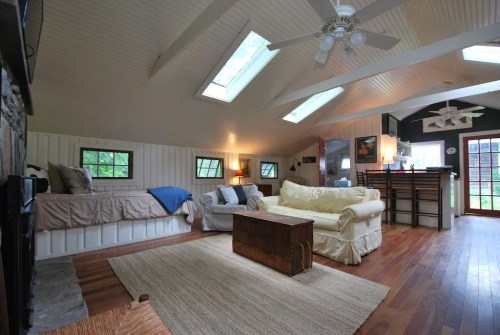 Cozy living space with skylights, wooden floors, a sofa, and a rustic coffee table, featuring a warm, inviting atmosphere.