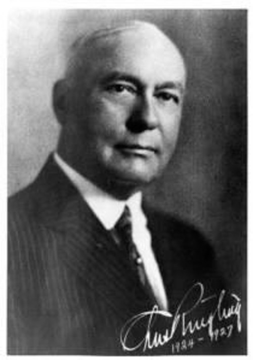 Black and white portrait of a man in a suit, with a signature at the bottom, dated 1924-1927.