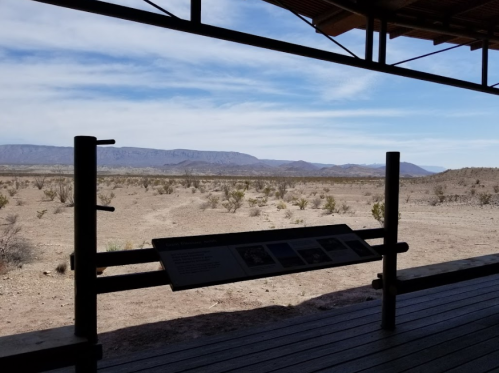 View from a shelter overlooking a barren landscape with distant mountains and a clear blue sky.