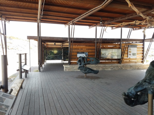 Interior of a museum exhibit featuring dinosaur fossils and informative displays, with wooden flooring and a modern design.
