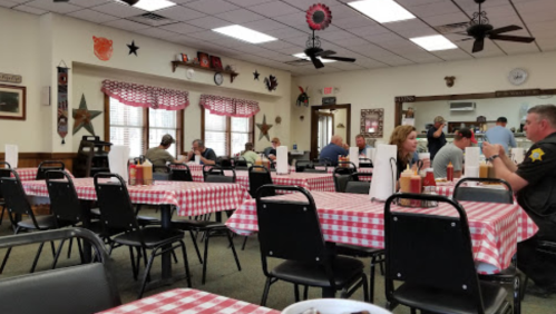 A cozy diner with checkered tablecloths, patrons dining, and a warm, rustic decor featuring stars and wall art.