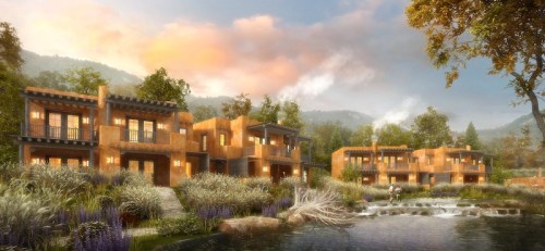 A serene landscape featuring modern adobe-style buildings by a tranquil stream, surrounded by lush greenery and mountains.