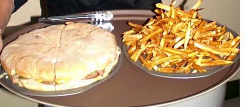 A large sandwich on a tray next to a generous serving of golden French fries.