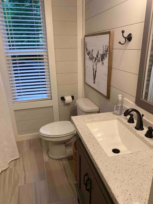 A modern bathroom featuring a toilet, sink, and a decorative wall art piece above the sink.