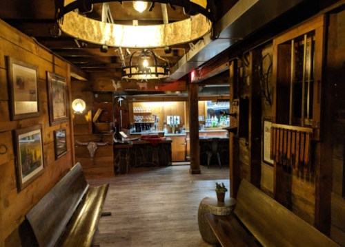 Cozy wooden interior of a rustic bar with a warm atmosphere, featuring a bar counter and seating area.