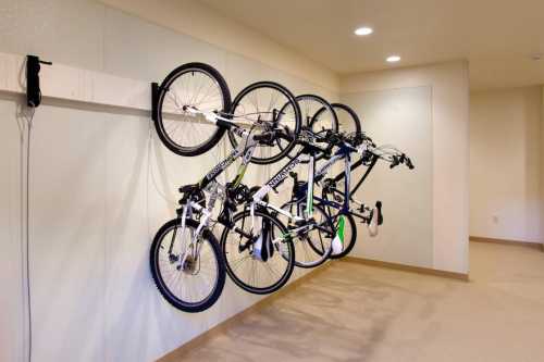 Five bicycles are hanging on a wall-mounted rack in a spacious, well-lit room.