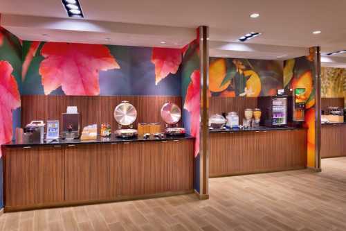 A buffet area with wooden counters, food displays, and colorful leaf-themed wall decor.