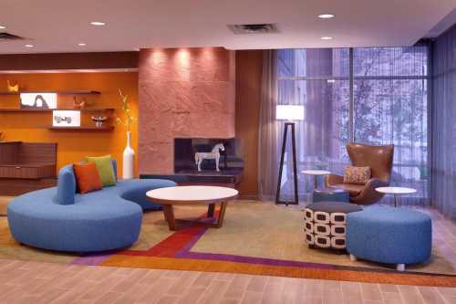 Modern lounge area featuring curved blue seating, a round table, and stylish decor in warm tones.