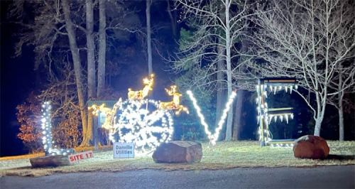 A nighttime scene featuring illuminated letters spelling "LOVE," with festive decorations and trees in the background.