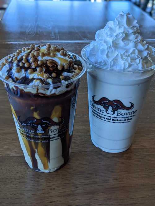 Two dessert cups: one with chocolate sauce, caramel, and nuts; the other a creamy vanilla shake topped with whipped cream.