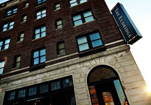 Exterior view of The Eldridge building, featuring brick architecture and large windows, with a sign above the entrance.