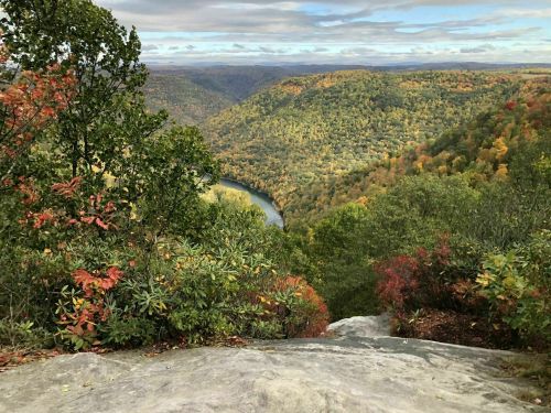 A scenic view of a river winding through colorful autumn foliage in a mountainous landscape.
