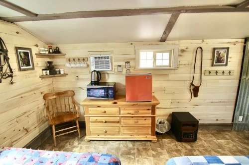 Cozy interior of a room featuring a wooden dresser, microwave, mini fridge, and rustic decor on the walls.