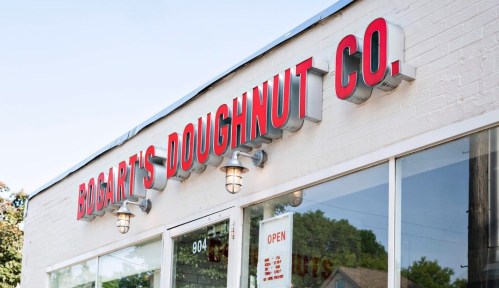 Sign for Bogart's Doughnut Co. on a white building, featuring red lettering and a large window.